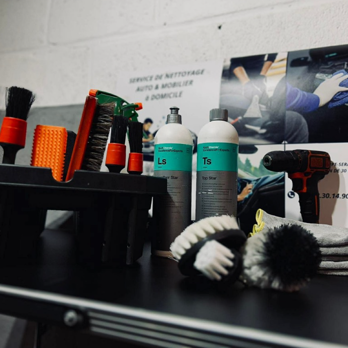 Produits et outils de nettoyage disposés sur un bureau avec des brosses et un perceuse.