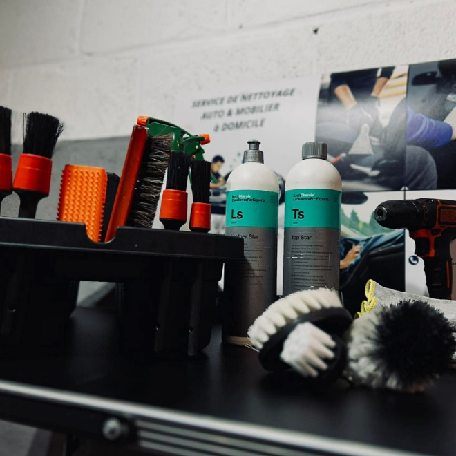 Accessoires de nettoyage, brosses, bouteilles de produit et un outil sur une surface de travail.