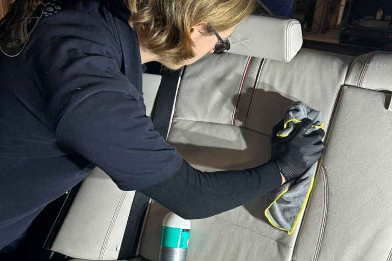 lavage de siège Person nettoyant un siège de voiture avec un chiffon et un produit de nettoyage.