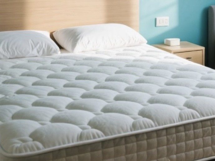 Matelas blanc avec des motifs ondulés sur un lit dans une chambre moderne.